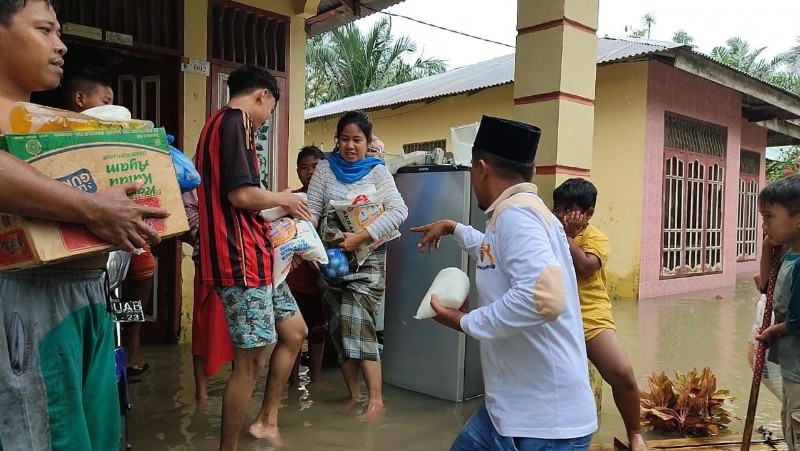 TAMPAK Relawan Kadin Batubara OK.Faizal dalam program Berbagi bersama PDIP Peduli dan Pemerintah mengarungi genangan air memberikan bantuan paket bahan pangan kepada warga yang terdampak bencana alam banjir di Kecamatan Datuk Limapuluh.