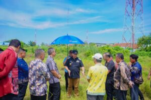 Kabag Protokol Batubara Widaruna panas-panasan memayungi Bupati Batubara Baharuddin Siagian saat meninjau lahan yang akan dijadikan sekolah rakyat program pemerintah pusat.